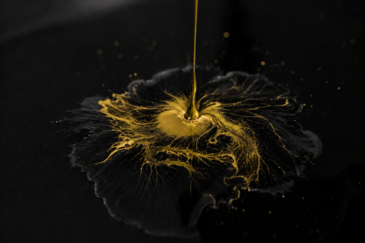 Gold lacquer being poured onto a black surface, creating a unique marbled pattern